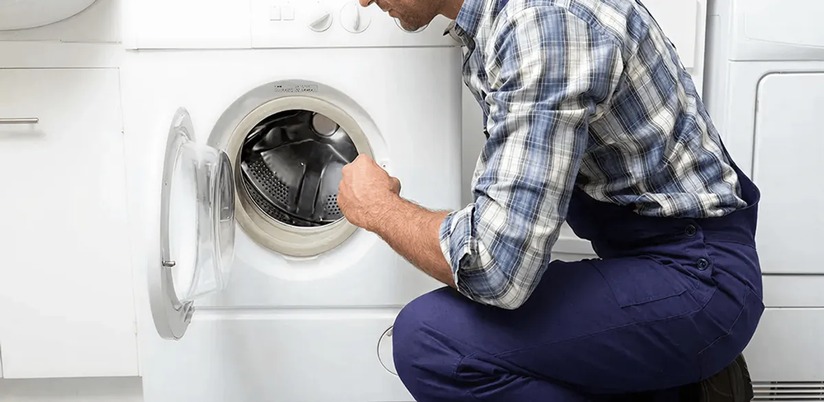 Handyman inspecting a dryer drum and internal parts for repair in Manchester, NH
