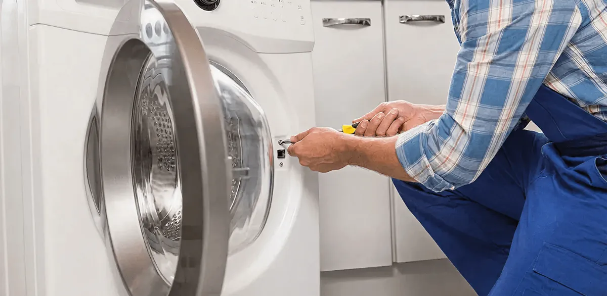 Handyman repairing a clothes dryer and checking electrical connections in Manchester, NH
