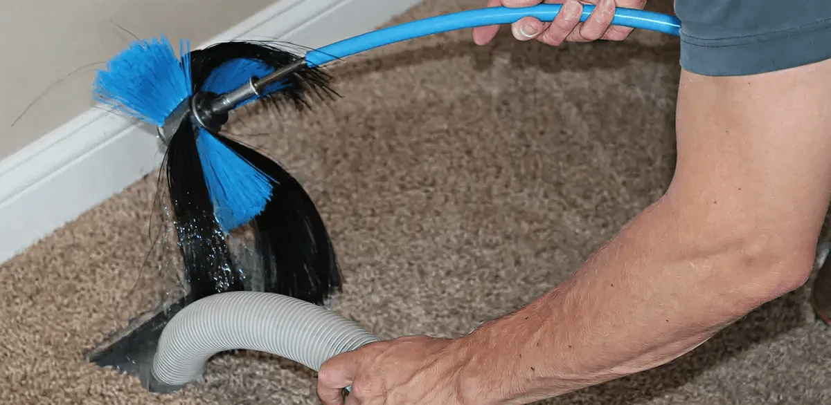 Dryer vent cleaning technician brushing lint from a vent line in Manchester, NH